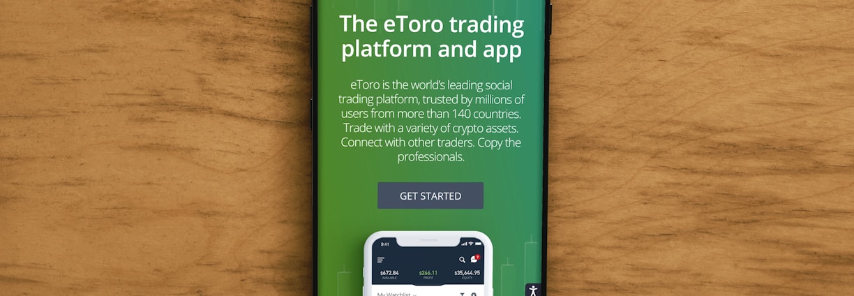 A smartphone displaying an advertisement for an online trading platform called eToro. The screen shows a green background with text promoting the platform as a leading social trading platform. A button labeled 'Get Started' is visible, along with a partial view of a mobile app screen below.